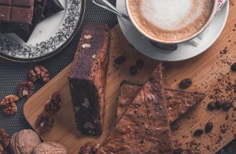Two triangular pieces of brownies accompanied by a latte, creating a delectable and comforting dessert pairing.