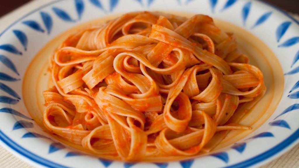 Pasta dressed in a luscious roasted pepper sauce, creating a colorful and flavorful dish.
